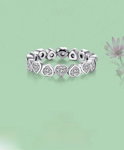 Macro shot of s925 silver eternity ring with heart-cut stones and claw setting