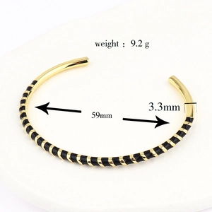 Detailed view showing 59mm diameter and 3.3mm width of the striped enamel gold cuff bracelet