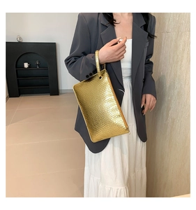 Detail of metallic gold envelope clutch bag featuring realistic crocodile skin texture