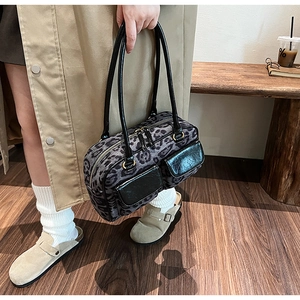 Close-up of leopard print bowling bag with dual black leather pockets and top handles