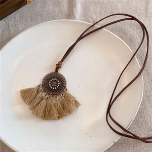 Détail d'un long collier de pull bohème avec pendentif mandala et glands kaki
