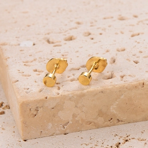 Close-up of gold irregular organic shaped stud earrings on natural beige stone