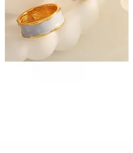 Close-up of vintage C-shaped earrings in 18K gold plated steel with white enamel detail