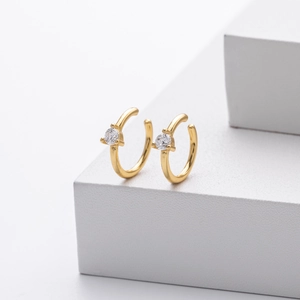 Macro detail of gold-plated silver C-shaped ear cuff featuring a clear zircon stone