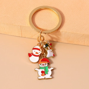 Close-up of golden metal keychain featuring enamel snowman, gingerbread man and stocking charms
