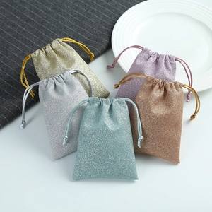 Detailed view of drawstring gift bags in shimmering gold, silver, and blue glitter texture