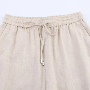 Detailed close-up of elastic waistband with linen texture and drawstring on beige shorts