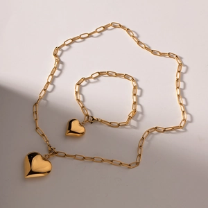 Detail of golden paperclip chain necklace and bracelet with hollow heart pendants