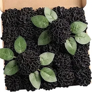 Close-up of artificial black dahlias and green leaves inside a shipping box