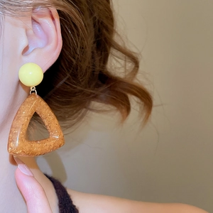 Close-up of amber resin triangle earrings with cream yellow studs and gold flakes