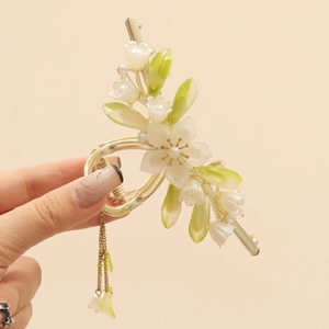 Detailed view of lily of the valley hair claw with cream petals and gold metal finish
