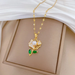 Detail of gold flower necklace with pearl center, green gems, and pavé crystal petals