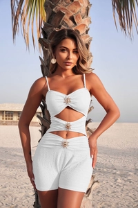 Close-up of white textured two-piece swimwear with gold sun metal buckle details