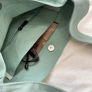 Dettaglio della borsa in tela verde menta con tasca interna con cerniera e chiusura magnetica