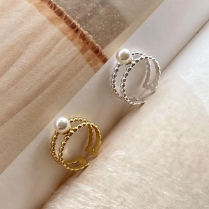 Detailed view of adjustable pearl rings in gold and silver with double beaded bands