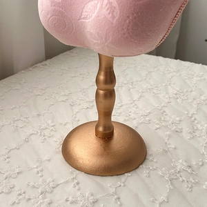 Detail of pink embossed velvet jewelry stand with a golden base on white lace