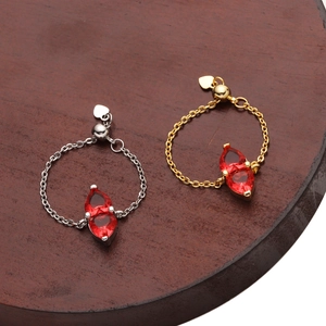 Detail of adjustable chain rings with marquise red zircons and heart charms in gold and silver