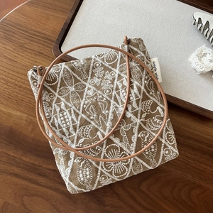 Close-up of khaki canvas crossbody bag with white embroidery and leather strap
