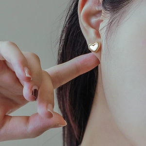 Elegant gold-plated heart stud earrings with white mother of pearl inlay on model