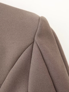 Detailaufnahme der Schulternähte und Wolltextur eines langen braunen Mantels im Brit-Stil