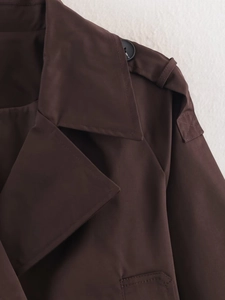 Detailed close-up of dark brown trench coat lapels, epaulets and fine double stitching