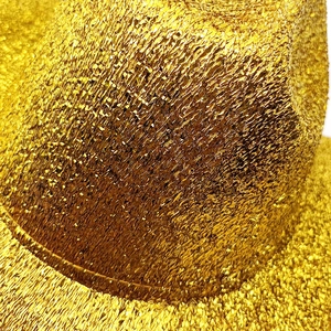Macro detail of sparkling gold sequin texture on festive wool felt cowboy party hat