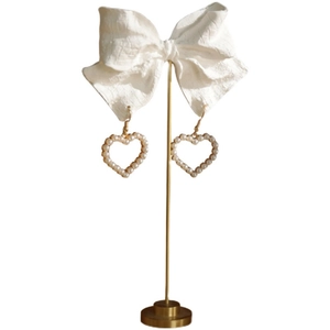 Elegant heart-shaped pearl earrings with gold hooks on a white decorative display