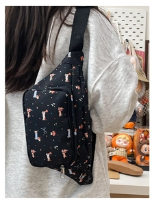Close-up of cute cartoon dog pattern on black crossbody chest bag worn by a person