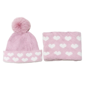 Dettaglio del set cappello e sciarpa in maglia rosa con cuori e morbido pompon in pelliccia