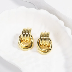 Detailed view of gold knotted triple hoop earrings on a white shell display plate