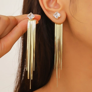 Close-up of golden tassel earrings with a large square-cut rhinestone and hanging chains