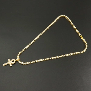 Macro shot of gold tennis chain with pearl and diamond-encrusted Ankh cross pendant