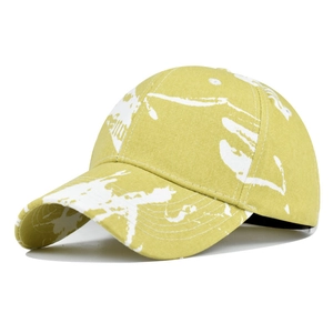 Detail of yellow tie-dye baseball cap with white ink splatter print and reinforced seams