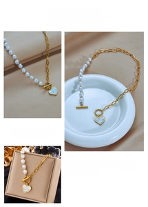 Détail du collier de perles avec boucle OT dorée et pendentif cœur bleu