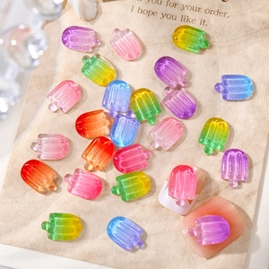 Macro detail of colorful resin ice cream popsicle nail charms on a finger model