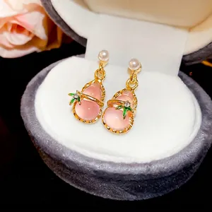 Gourd pearl drop earrings with pink resin and gold edging on a velvet jewelry box