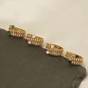 Detail of four 18K gold plated rings with colorful heart zircons on black stone