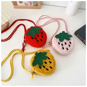 Detail view of plush strawberry crossbody bags in red, pink, and yellow for kids