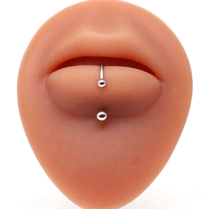 Silver stainless steel lip stud piercing displayed on a realistic silicone lip model