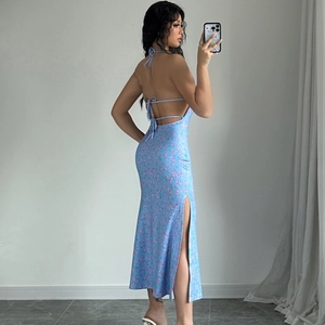 Detail of blue floral halter dress with high slit and open back design on model