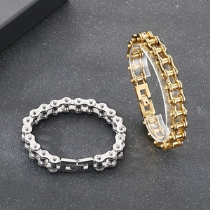 Close-up of gold and silver stainless steel bicycle chain bracelets for men on a dark surface