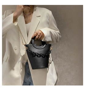 Detail of black PU leather bucket bag with gold and thick black chain decorative straps