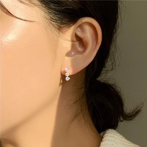 Close-up of triple zircon flower earrings in 925 silver on a female model ear