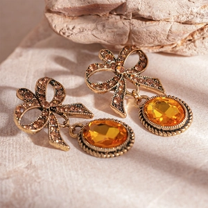 Close-up of vintage bow earrings with orange oval gemstones and shiny rhinestones