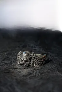 Detailed macro view of vintage punk skull ring with wings on a dark volcanic rock