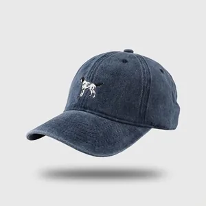 Close-up of small dog embroidery on a vintage washed navy blue denim baseball cap