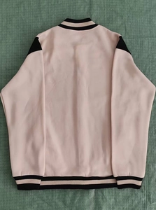 Rear view of pink baseball jacket featuring black shoulder panels and striped rib-knit trim