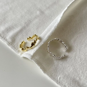 Irregular textured gold and silver minimalist open rings on white fabric surface