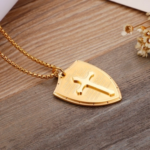 Detail of golden shield pendant with cross engraving and Bible verse on wooden background