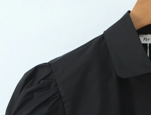 Λεπτομέρεια από φουσκωτά μανίκια και μυτερό γιακά σε μαύρο vintage πουκάμισο με κουμπιά